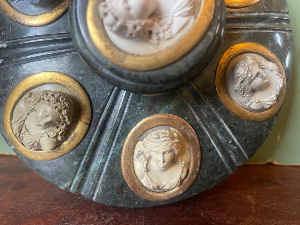 A circular dark green carved Prato Verde marble inkstand with fluted sides, set with six oval carved Vesuvian lava portrait cameos framed in brass mounts around a central raised finial. View XI
