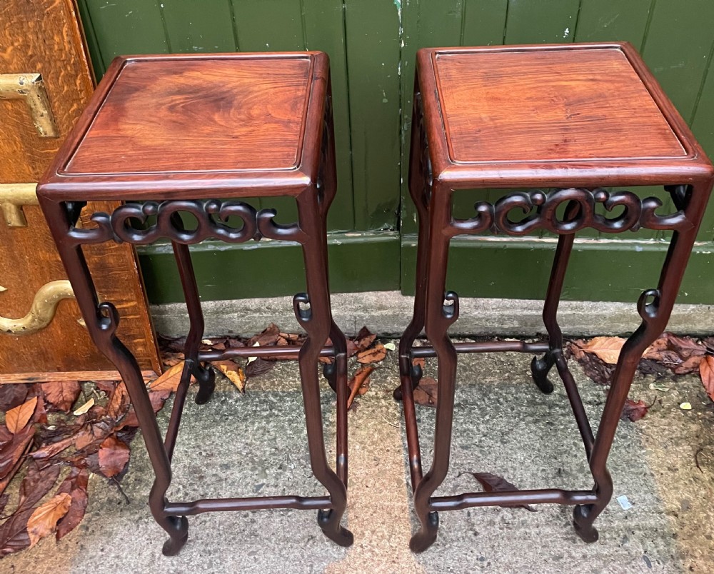 A pair of tall late 19th-century Chinese Qing Dynasty dark hardwood stands featuring square tops, openwork carved scroll aprons, and slender serpentine legs. View III