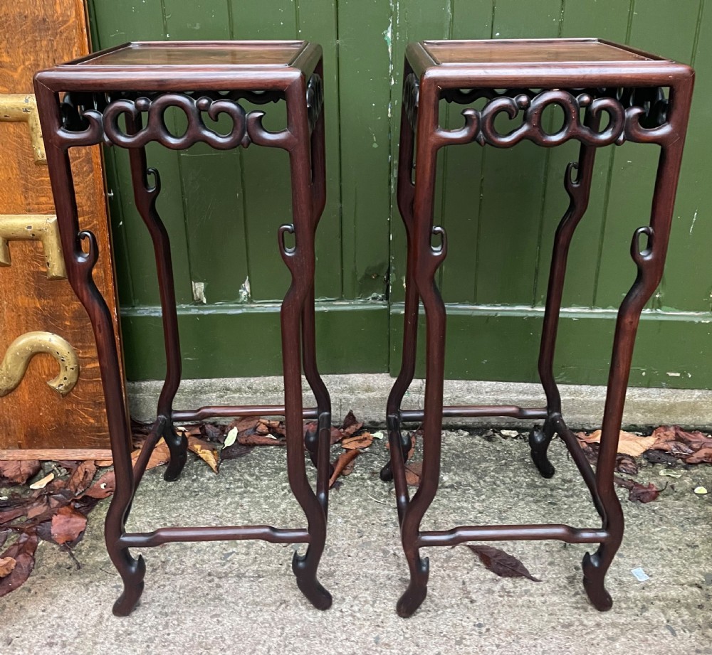 A pair of tall late 19th-century Chinese Qing Dynasty dark hardwood stands featuring square tops, openwork carved scroll aprons, and slender serpentine legs. View V