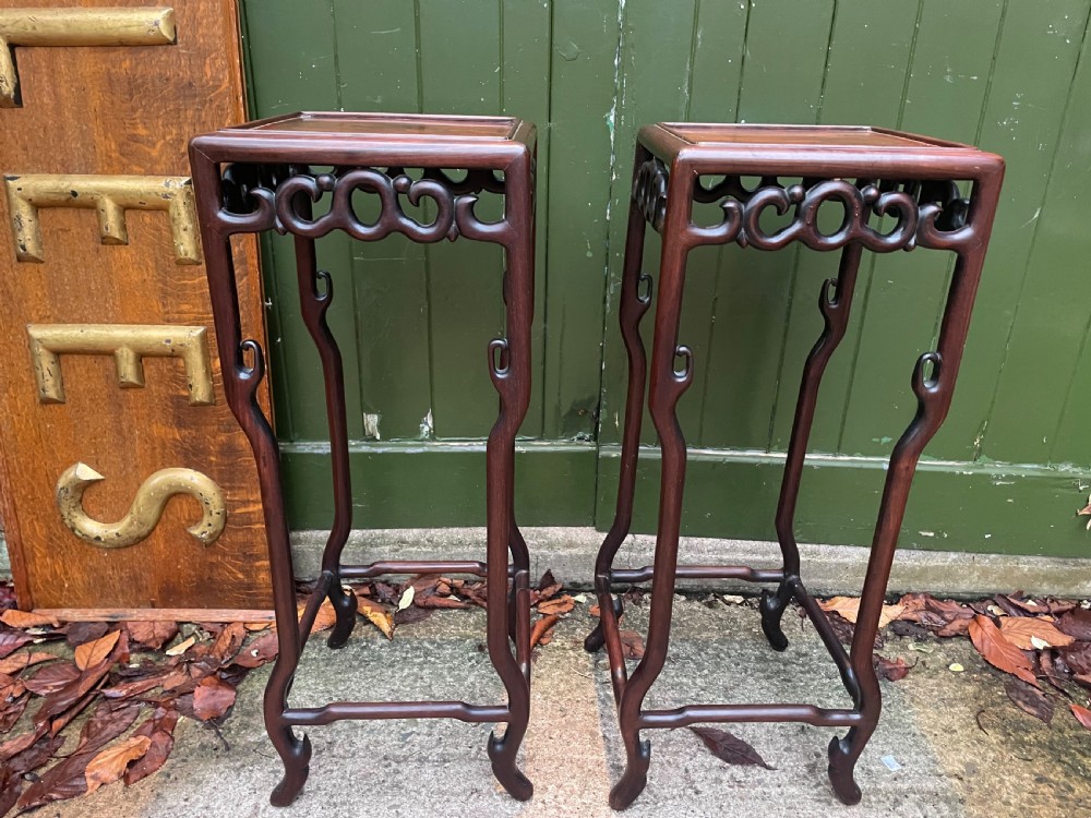 A pair of tall late 19th-century Chinese Qing Dynasty dark hardwood stands featuring square tops, openwork carved scroll aprons, and slender serpentine legs. View VI