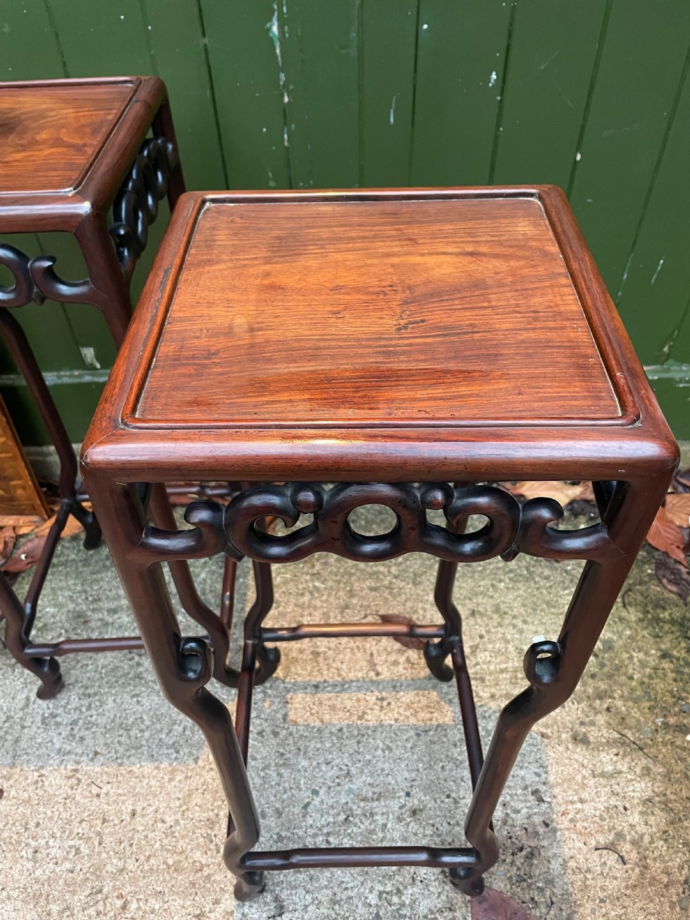 A pair of tall late 19th-century Chinese Qing Dynasty dark hardwood stands featuring square tops, openwork carved scroll aprons, and slender serpentine legs. View X