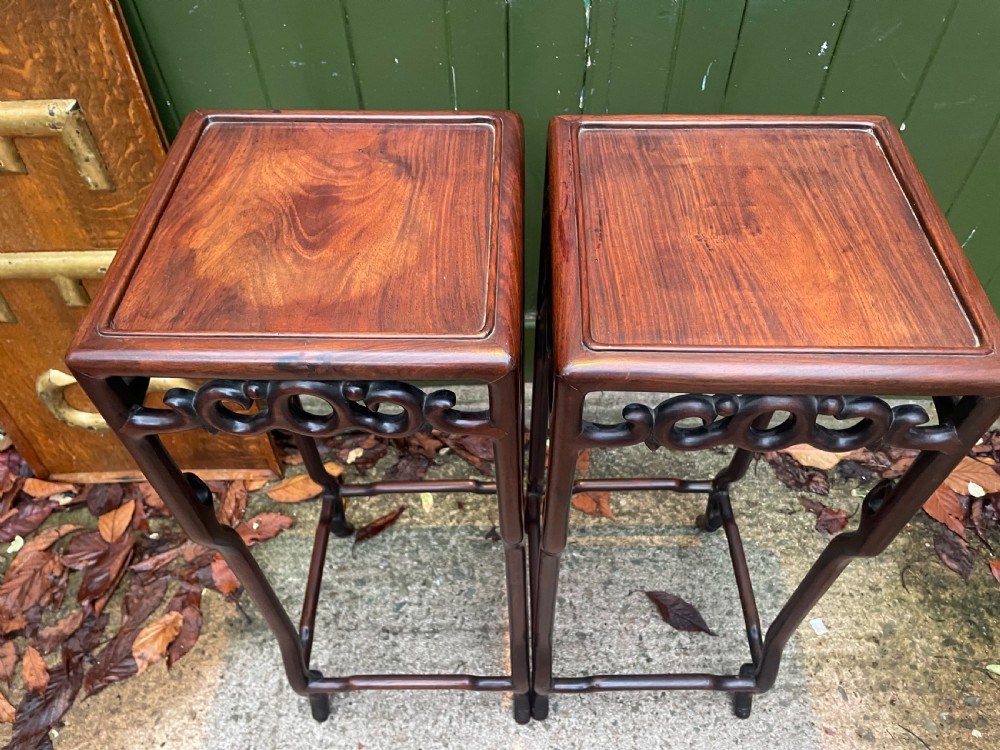 A pair of tall late 19th-century Chinese Qing Dynasty dark hardwood stands featuring square tops, openwork carved scroll aprons, and slender serpentine legs. View XIX