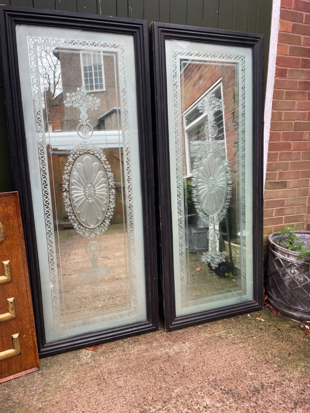 A pair of tall rectangular Edwardian wall mirrors featuring detailed etched floral urns and central oval medallions in dark wooden frames. View V