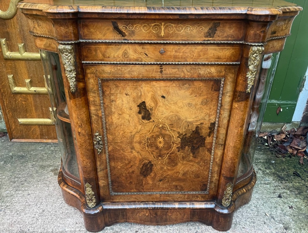 A mid-19th century Victorian burr walnut credenza featuring boxwood marquetry inlay, gilded ormolu mounts, a central drawer, and curved glass side display doors. View III