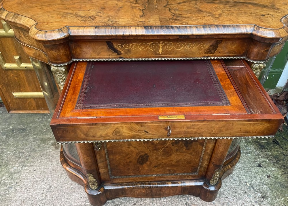 A mid-19th century Victorian burr walnut credenza featuring boxwood marquetry inlay, gilded ormolu mounts, a central drawer, and curved glass side display doors. View VI