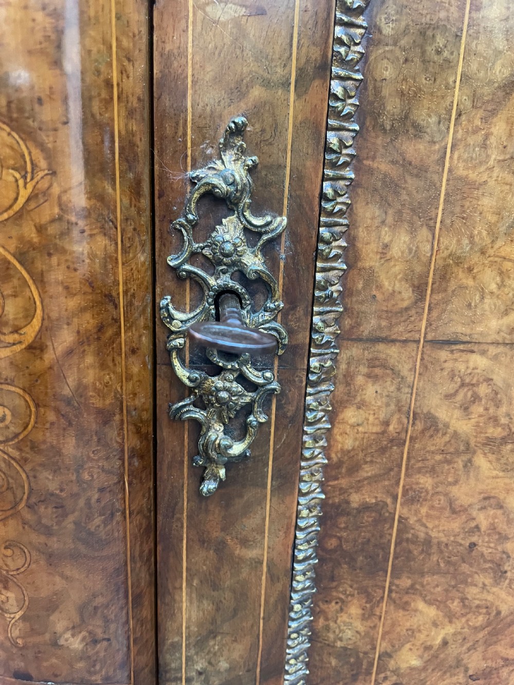 A mid-19th century Victorian burr walnut credenza featuring boxwood marquetry inlay, gilded ormolu mounts, a central drawer, and curved glass side display doors. View XII