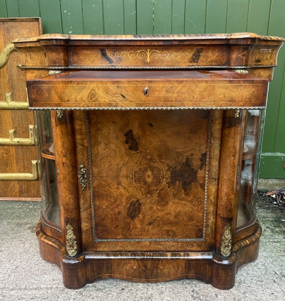 A mid-19th century Victorian burr walnut credenza featuring boxwood marquetry inlay, gilded ormolu mounts, a central drawer, and curved glass side display doors. View XXII