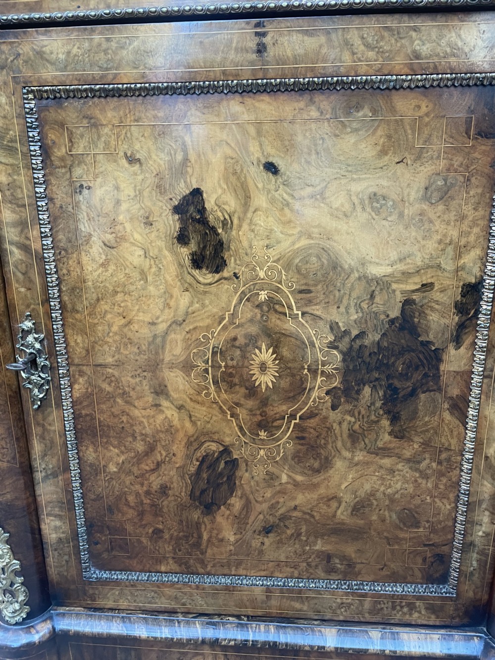 A mid-19th century Victorian burr walnut credenza featuring boxwood marquetry inlay, gilded ormolu mounts, a central drawer, and curved glass side display doors. View IX