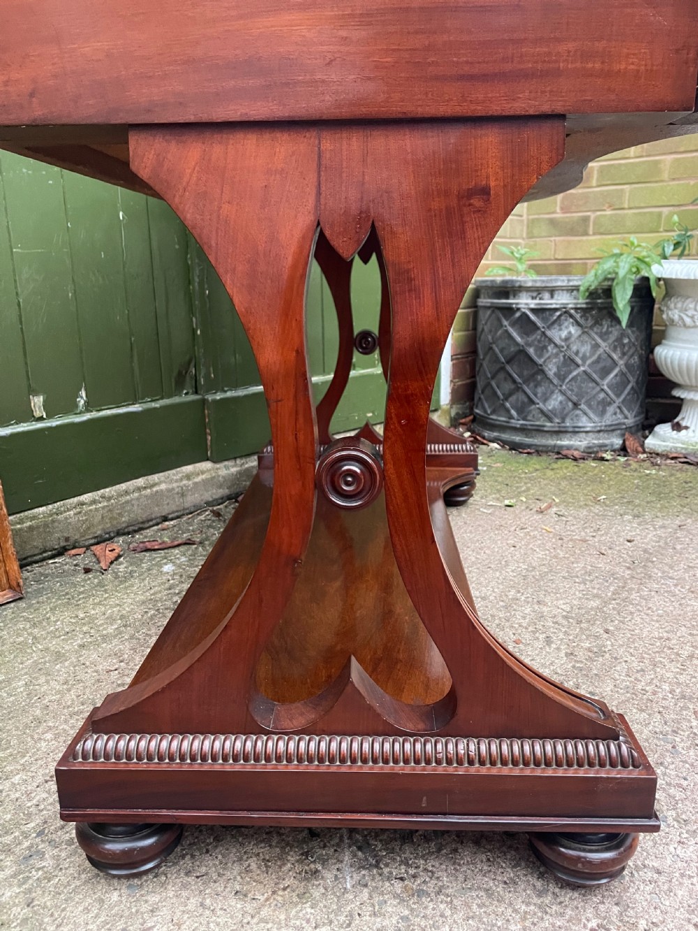 An early nineteenth-century mahogany serpentine side table featuring two drawers, a gallery top, curved end supports, and a lower shelf. View XIII