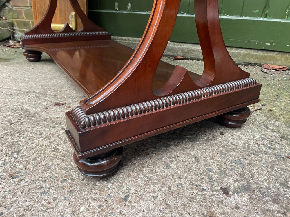 An early nineteenth-century mahogany serpentine side table featuring two drawers, a gallery top, curved end supports, and a lower shelf. View XIV