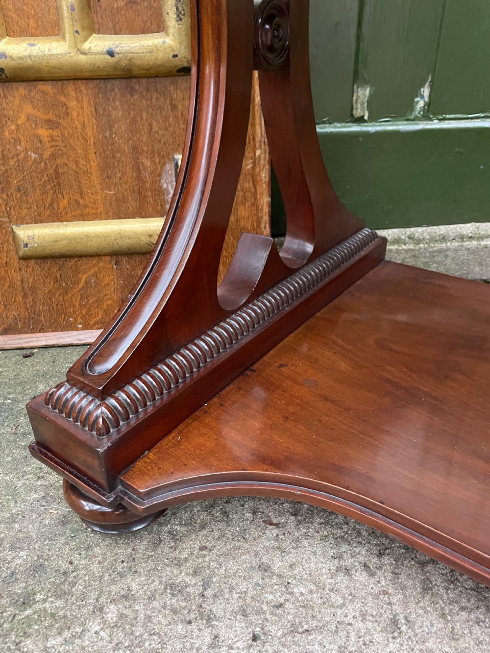 An early nineteenth-century mahogany serpentine side table featuring two drawers, a gallery top, curved end supports, and a lower shelf. View XVIII