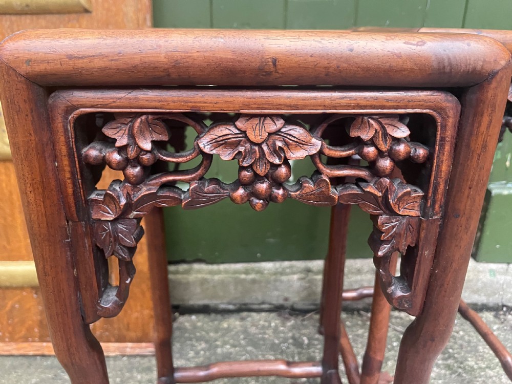 A pair of late nineteenth to early twentieth century Chinese Qing Dynasty carved huali hardwood side tables featuring openwork grapevine aprons and organic faux-bamboo legs. View X