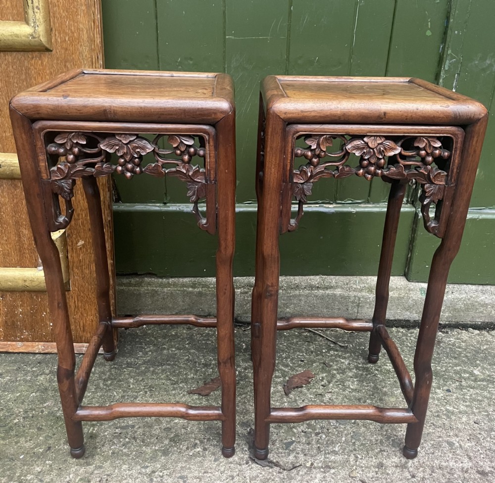 A pair of late nineteenth to early twentieth century Chinese Qing Dynasty carved huali hardwood side tables featuring openwork grapevine aprons and organic faux-bamboo legs.