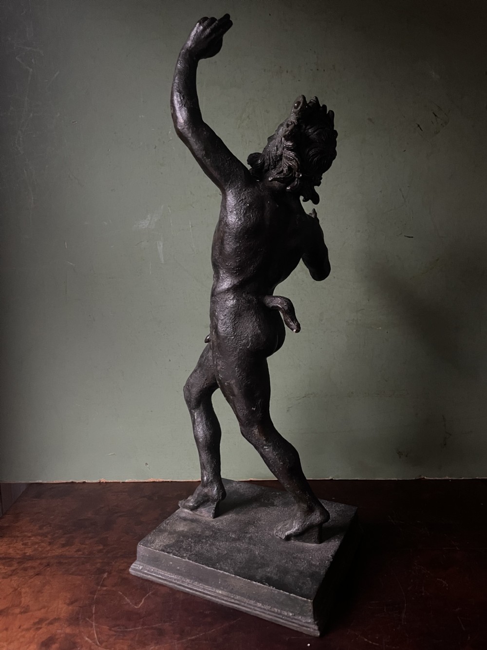 A late nineteenth-century dark patinated bronze sculpture depicting the Dancing Faun of Pompeii standing in a dynamic pose on a rectangular bronze base. View III