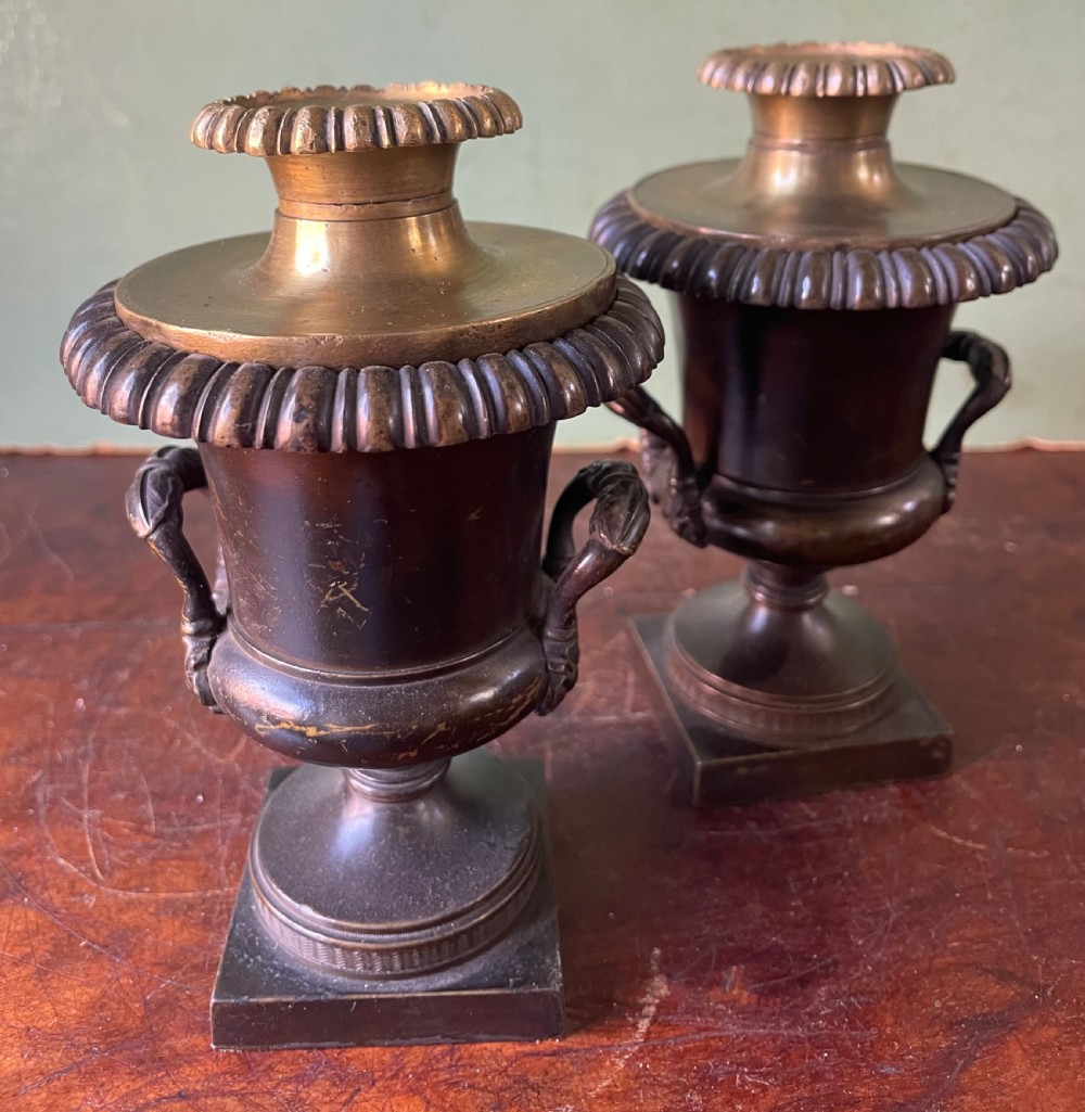 A pair of early nineteenth-century Regency dark brown bronze cassolettes with campana-shaped bodies, double loop handles, gadrooned lids topped with finials, resting on square plinth bases. View V