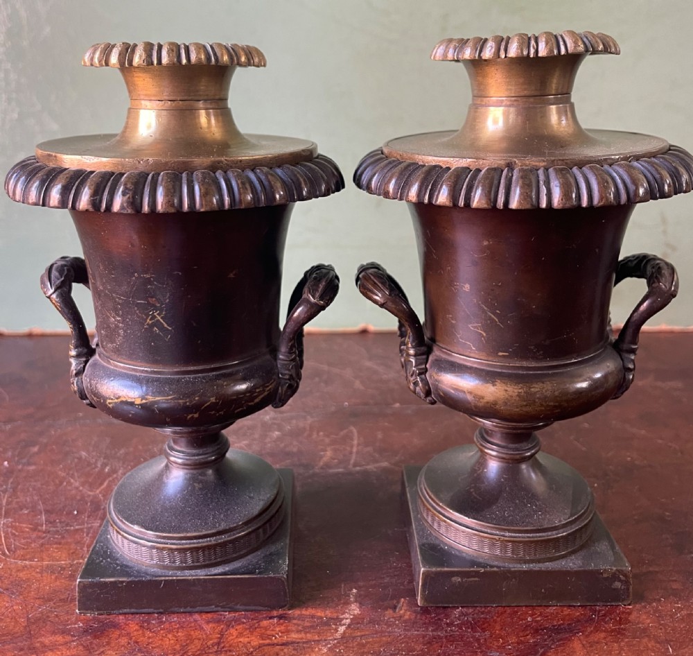 A pair of early nineteenth-century Regency dark brown bronze cassolettes with campana-shaped bodies, double loop handles, gadrooned lids topped with finials, resting on square plinth bases. View VI