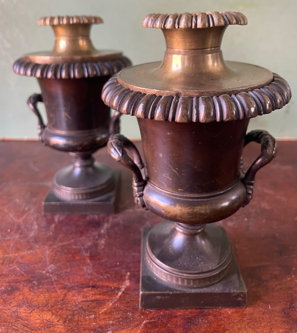 A pair of early nineteenth-century Regency dark brown bronze cassolettes with campana-shaped bodies, double loop handles, gadrooned lids topped with finials, resting on square plinth bases. View VIII