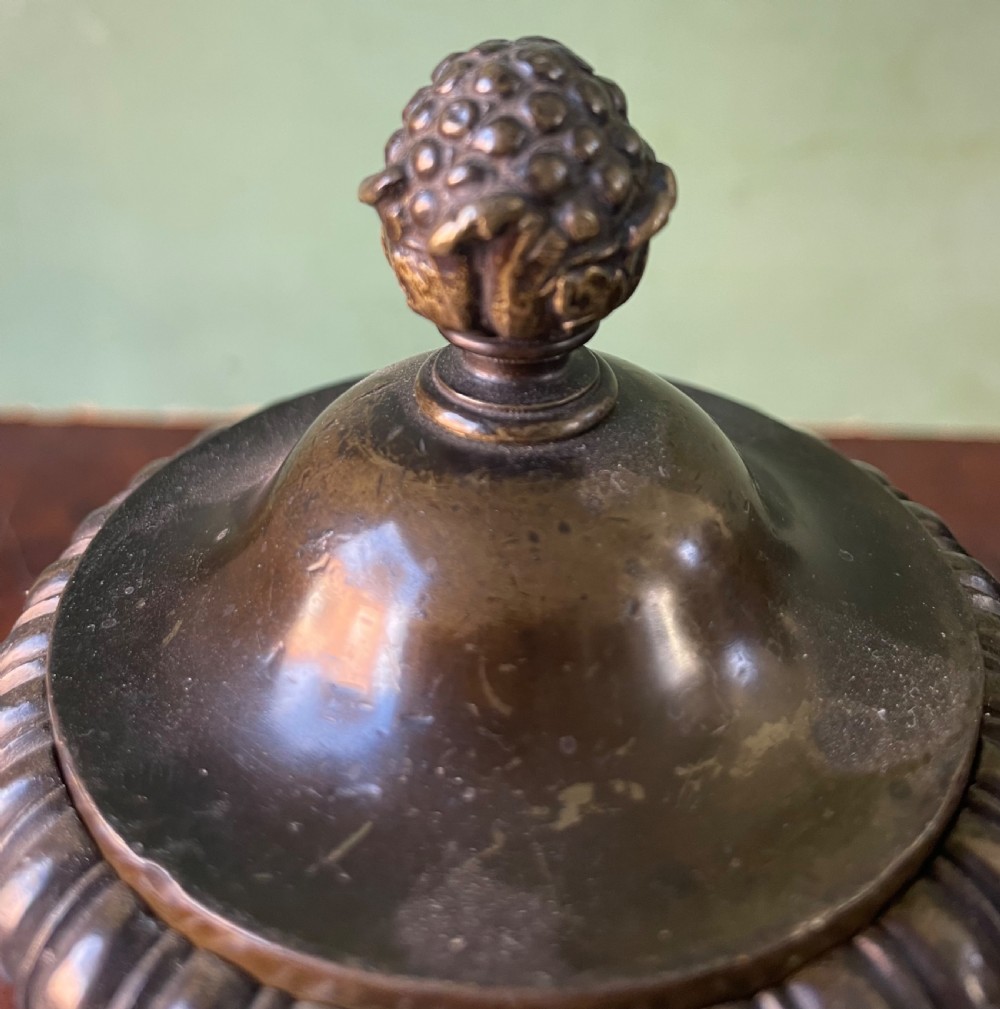 A pair of early nineteenth-century Regency dark brown bronze cassolettes with campana-shaped bodies, double loop handles, gadrooned lids topped with finials, resting on square plinth bases. View IX