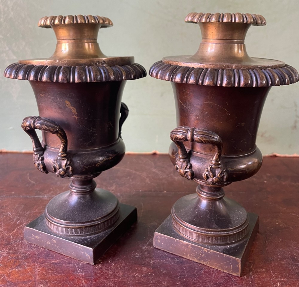 A pair of early nineteenth-century Regency dark brown bronze cassolettes with campana-shaped bodies, double loop handles, gadrooned lids topped with finials, resting on square plinth bases. View X