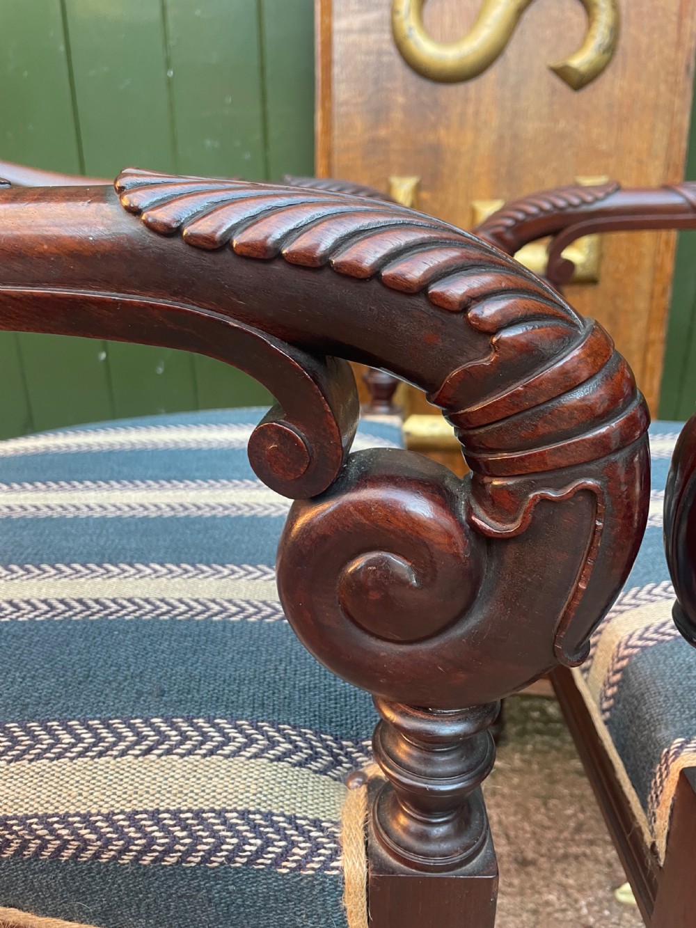A pair of early 19th-century carved mahogany salon armchairs featuring carved crest rails, scrolled armrests, turned front legs, and blue striped fabric upholstery. View VIII