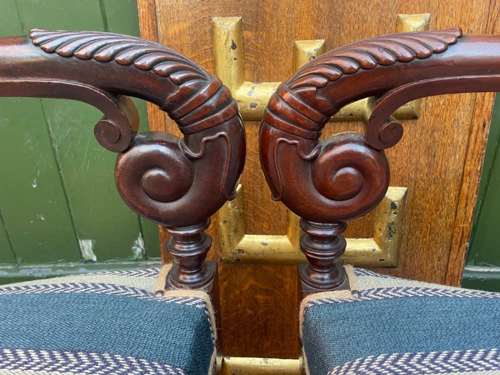 A pair of early 19th-century carved mahogany salon armchairs featuring carved crest rails, scrolled armrests, turned front legs, and blue striped fabric upholstery. View IX