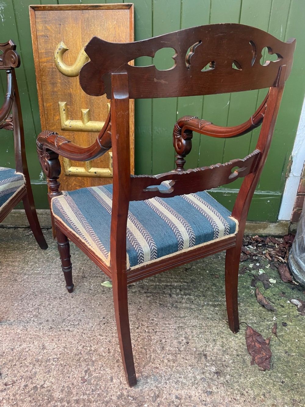 A pair of early 19th-century carved mahogany salon armchairs featuring carved crest rails, scrolled armrests, turned front legs, and blue striped fabric upholstery. View XIII