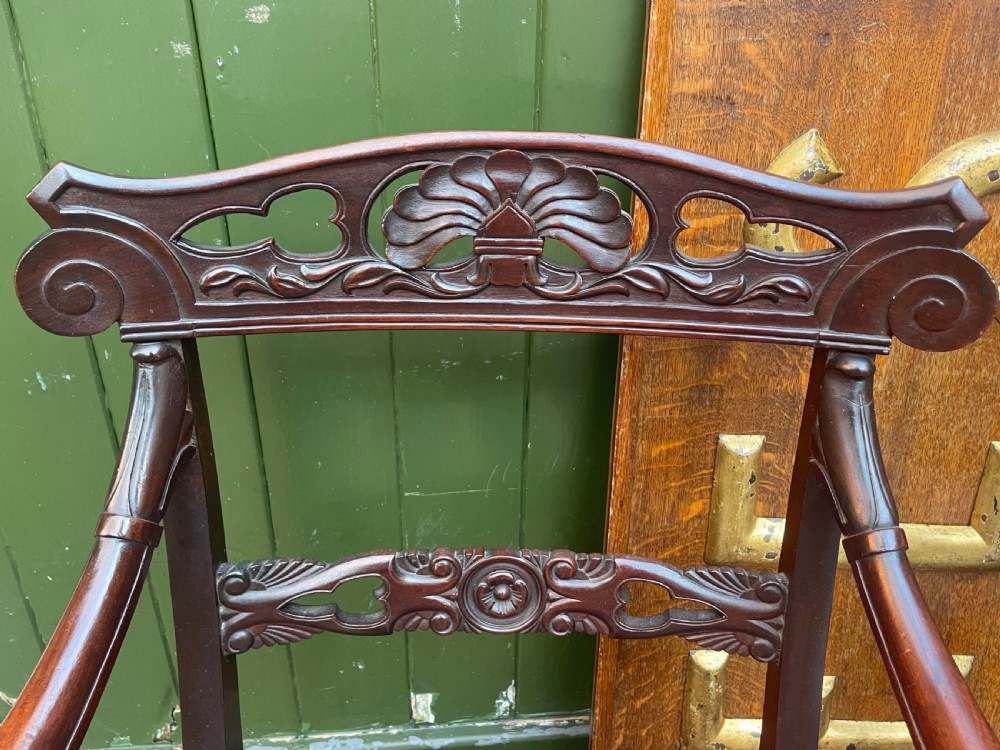 A pair of early 19th-century carved mahogany salon armchairs featuring carved crest rails, scrolled armrests, turned front legs, and blue striped fabric upholstery. View XV