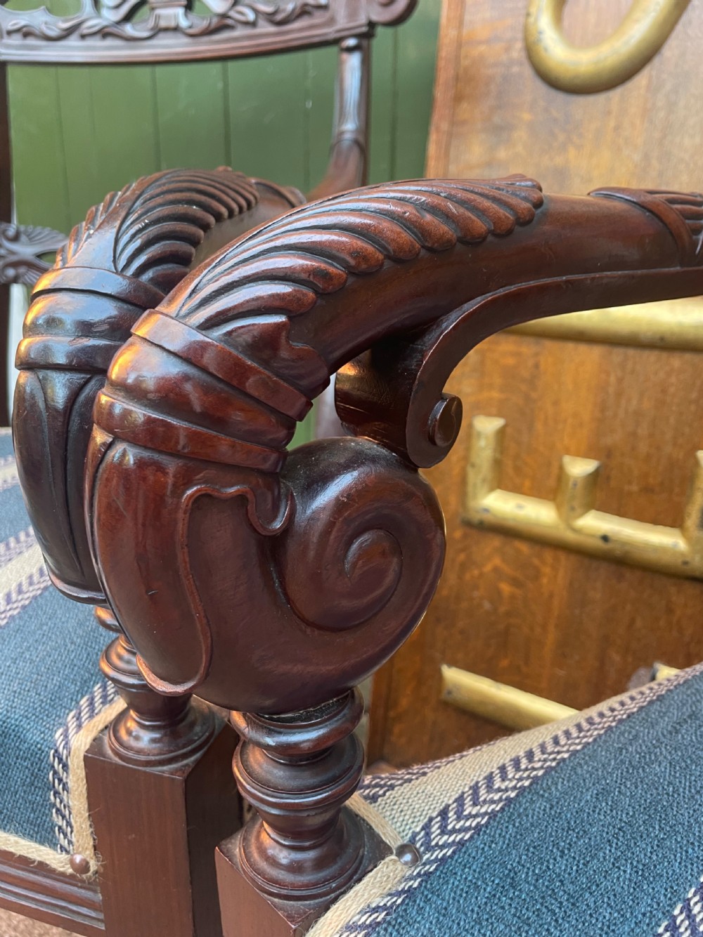 A pair of early 19th-century carved mahogany salon armchairs featuring carved crest rails, scrolled armrests, turned front legs, and blue striped fabric upholstery. View XIX