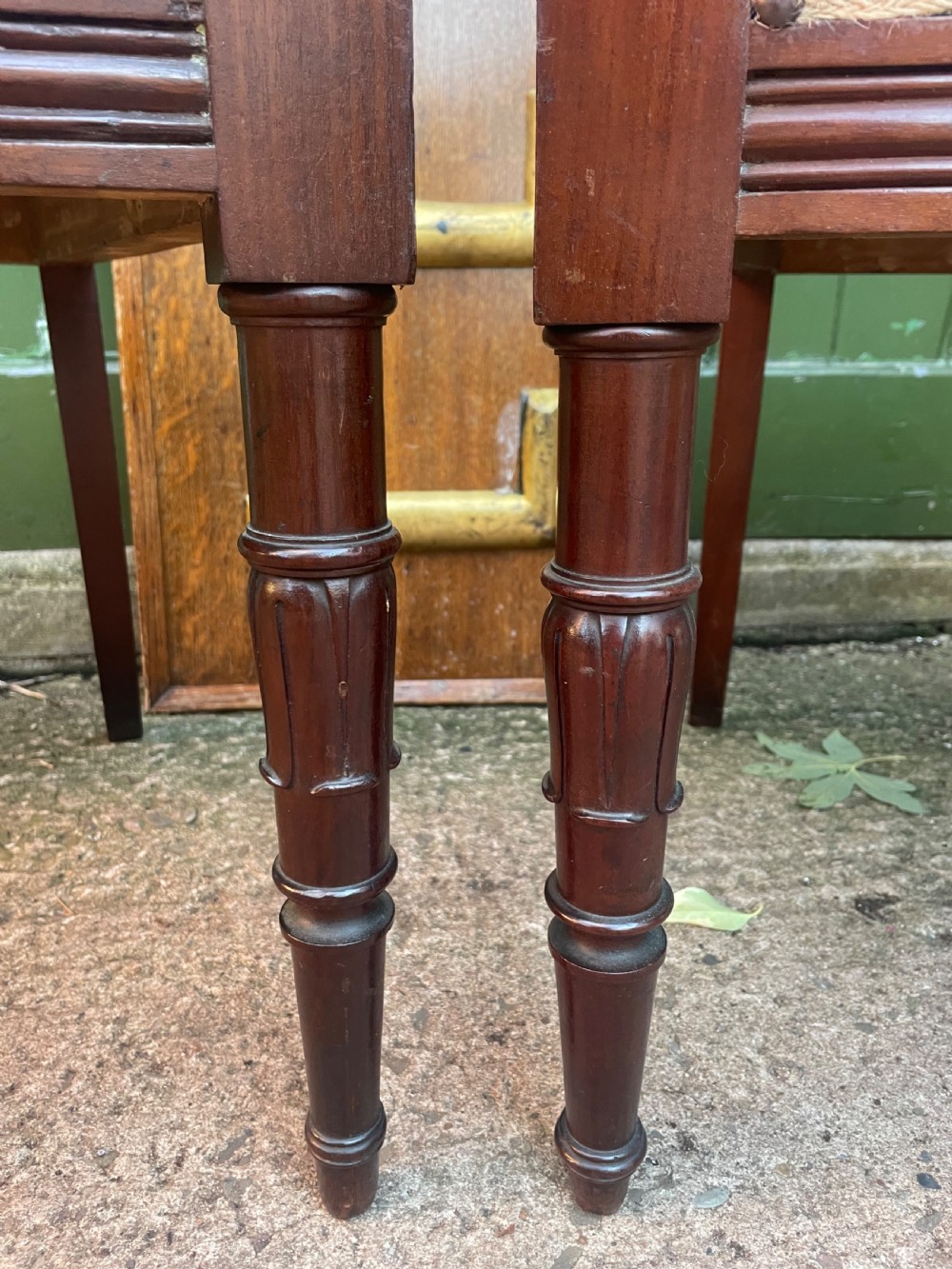 A pair of early 19th-century carved mahogany salon armchairs featuring carved crest rails, scrolled armrests, turned front legs, and blue striped fabric upholstery. View XX