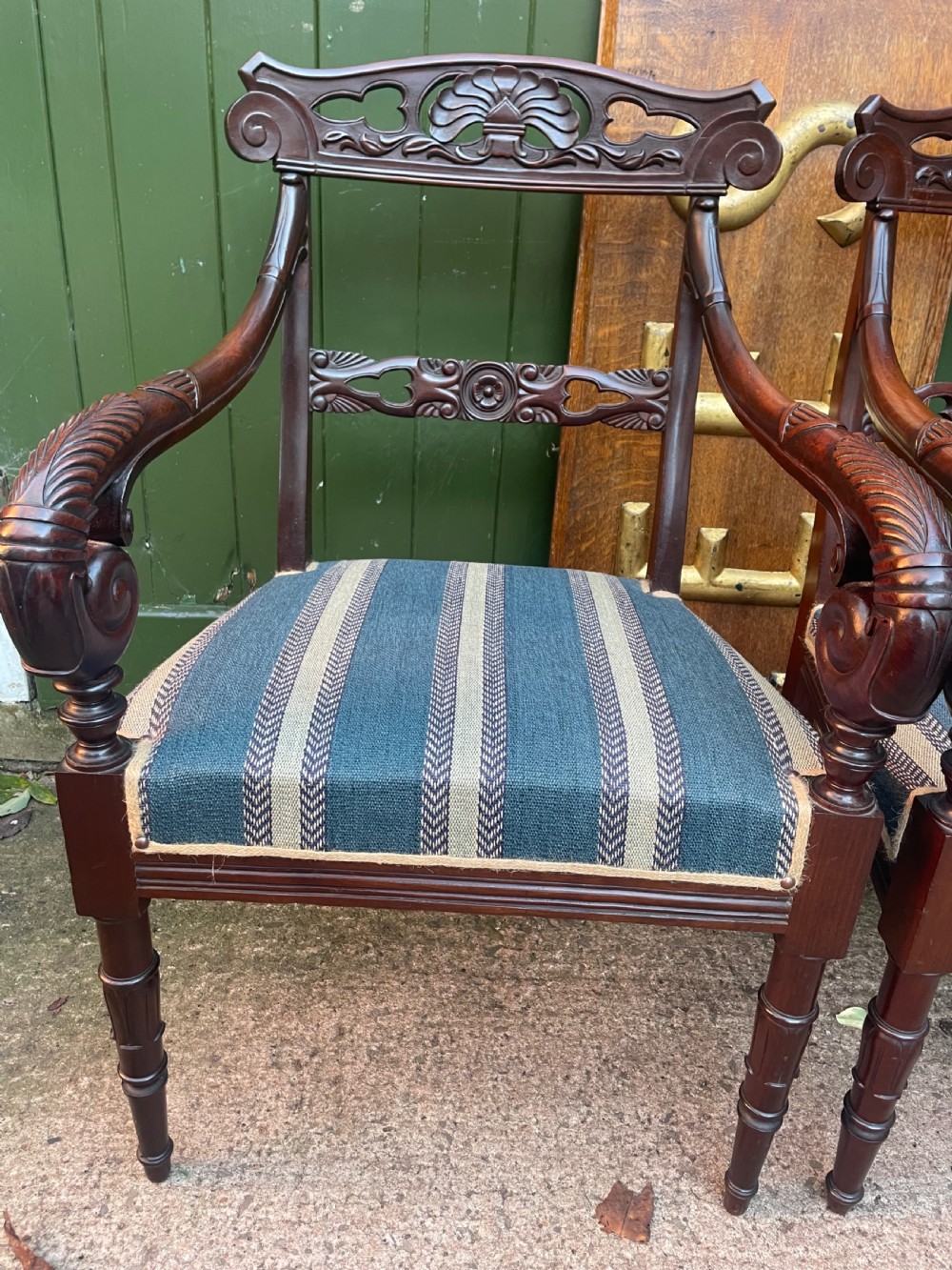 A pair of early 19th-century carved mahogany salon armchairs featuring carved crest rails, scrolled armrests, turned front legs, and blue striped fabric upholstery. View XXI