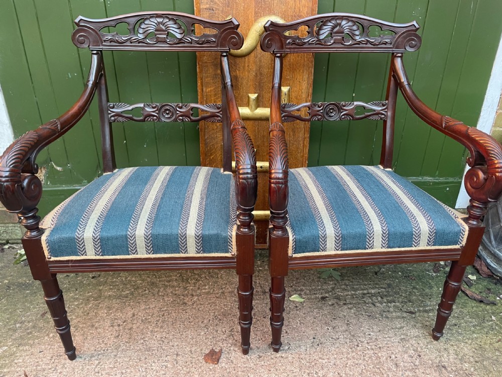 A pair of early 19th-century carved mahogany salon armchairs featuring carved crest rails, scrolled armrests, turned front legs, and blue striped fabric upholstery. View XXII