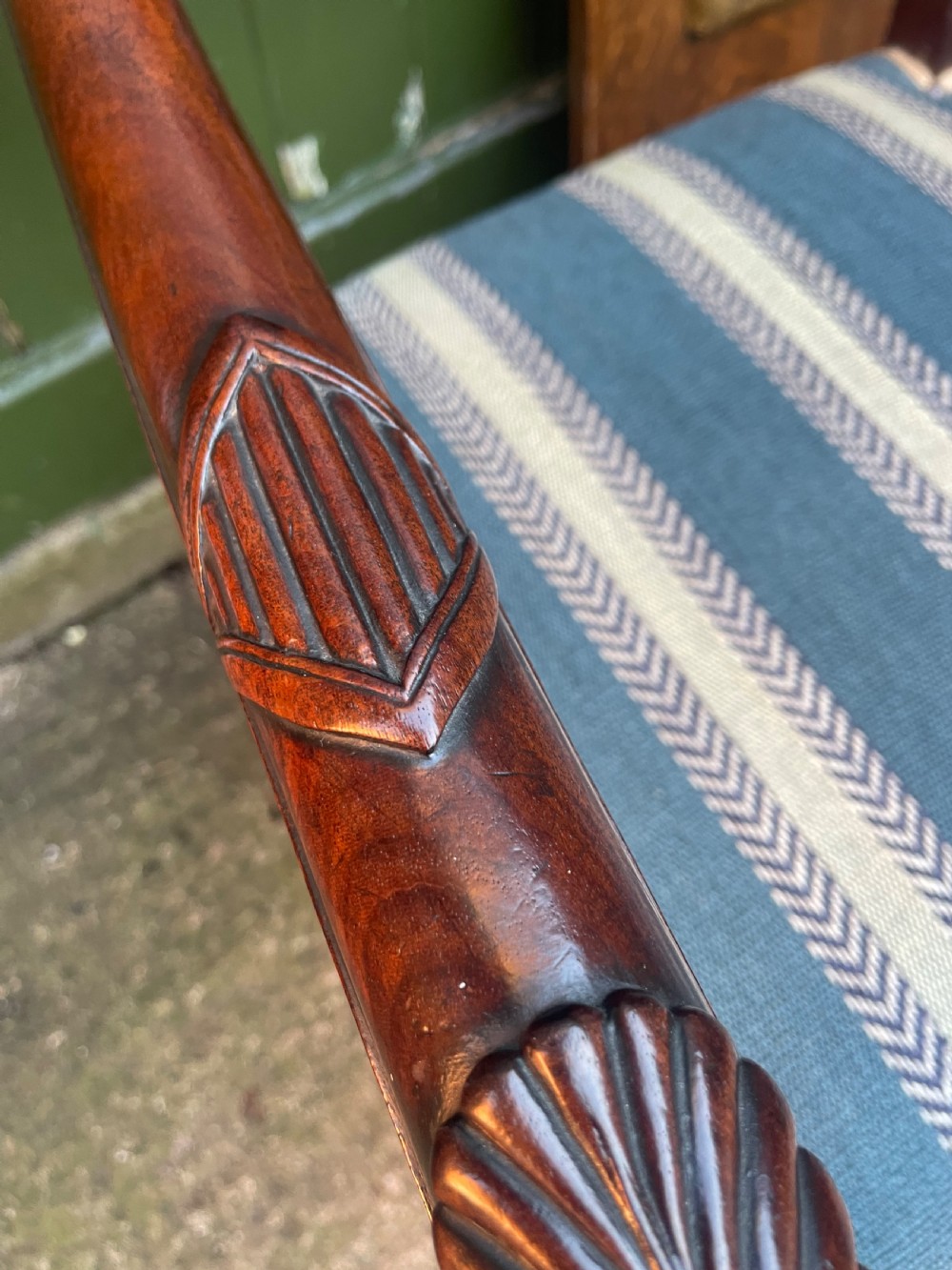 A pair of early 19th-century carved mahogany salon armchairs featuring carved crest rails, scrolled armrests, turned front legs, and blue striped fabric upholstery. View XXIII