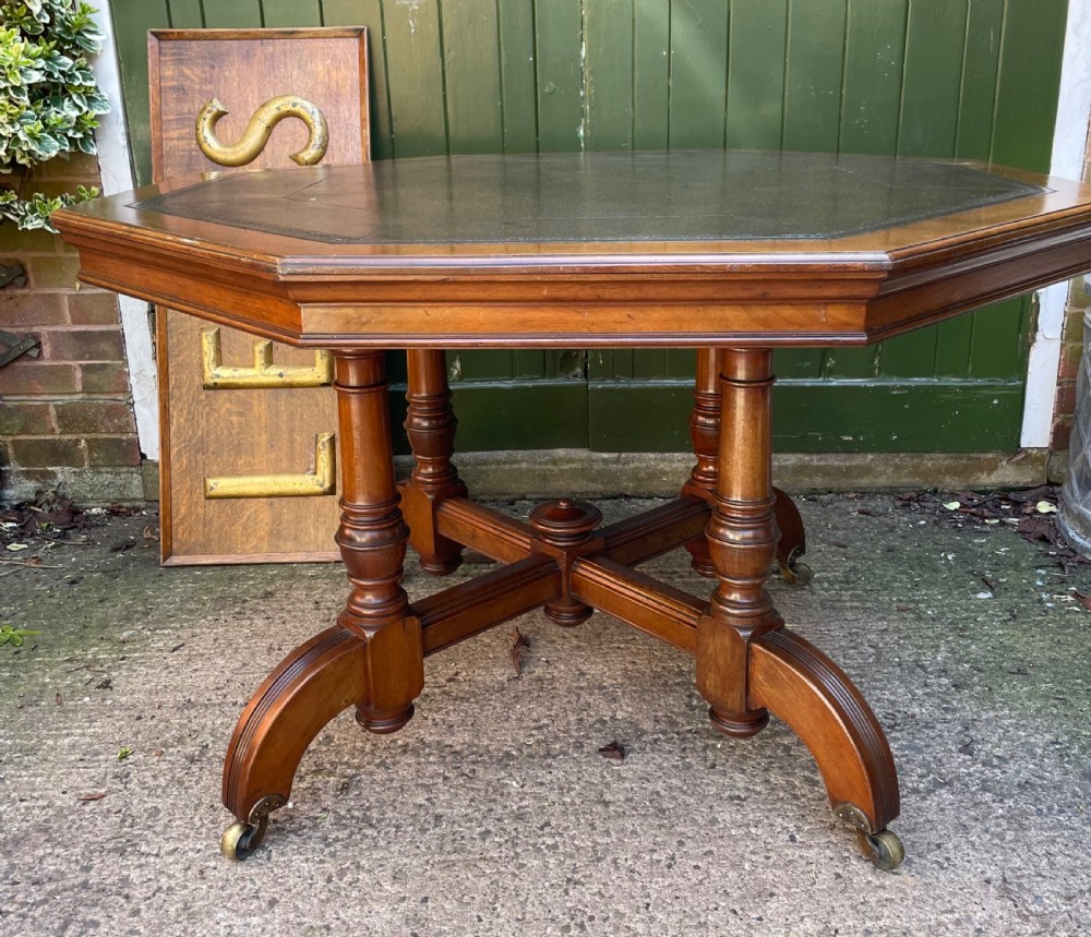 A late nineteenth-century octagonal walnut library table featuring a tooled dark leather inset top, turned legs, a cross stretcher, and brass castors. View II