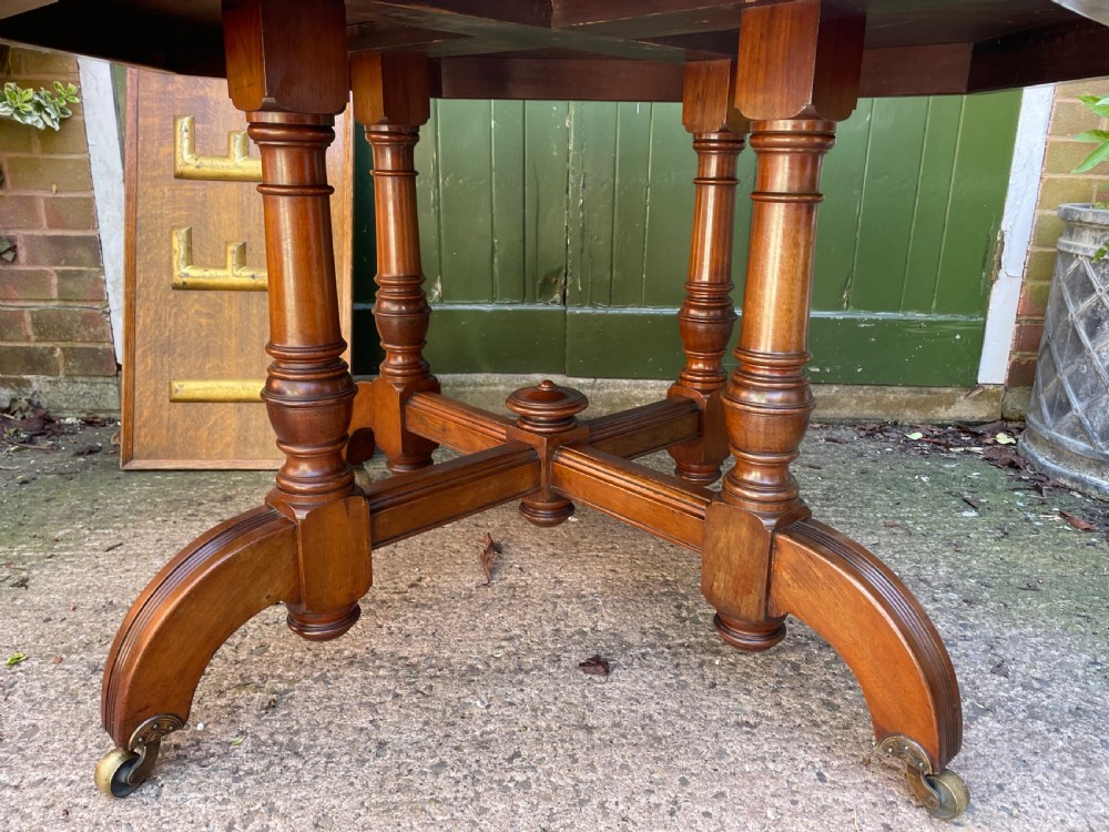 A late nineteenth-century octagonal walnut library table featuring a tooled dark leather inset top, turned legs, a cross stretcher, and brass castors. View V