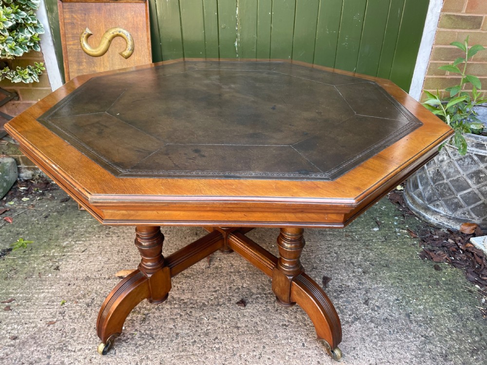 A late nineteenth-century octagonal walnut library table featuring a tooled dark leather inset top, turned legs, a cross stretcher, and brass castors. View VI