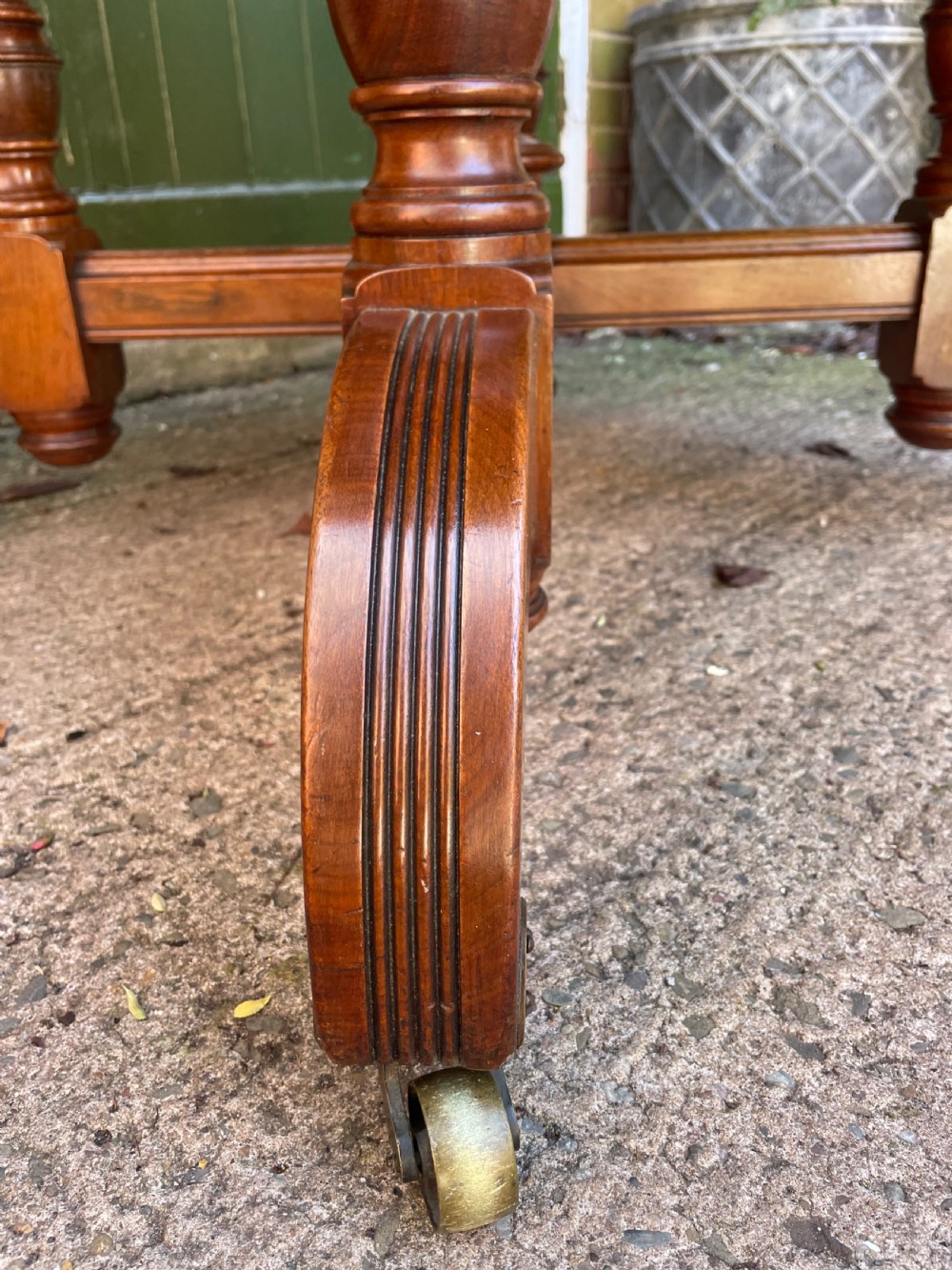 A late nineteenth-century octagonal walnut library table featuring a tooled dark leather inset top, turned legs, a cross stretcher, and brass castors. View VII