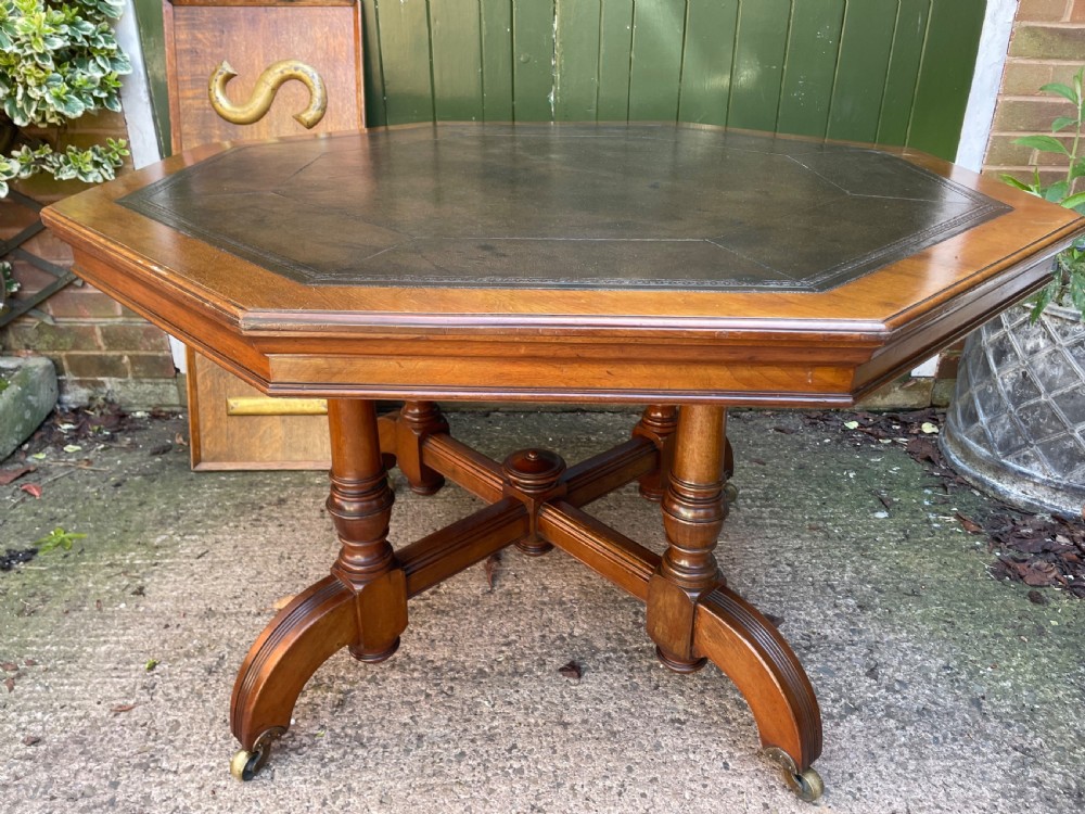 A late nineteenth-century octagonal walnut library table featuring a tooled dark leather inset top, turned legs, a cross stretcher, and brass castors. View XIII