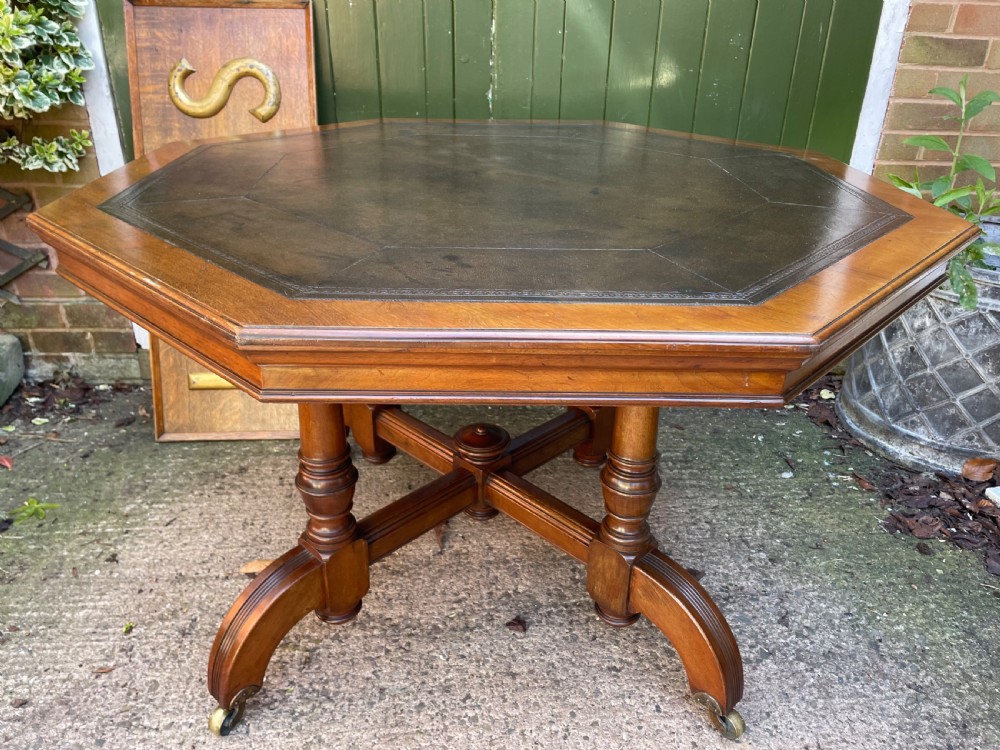 A late nineteenth-century octagonal walnut library table featuring a tooled dark leather inset top, turned legs, a cross stretcher, and brass castors. View XIV