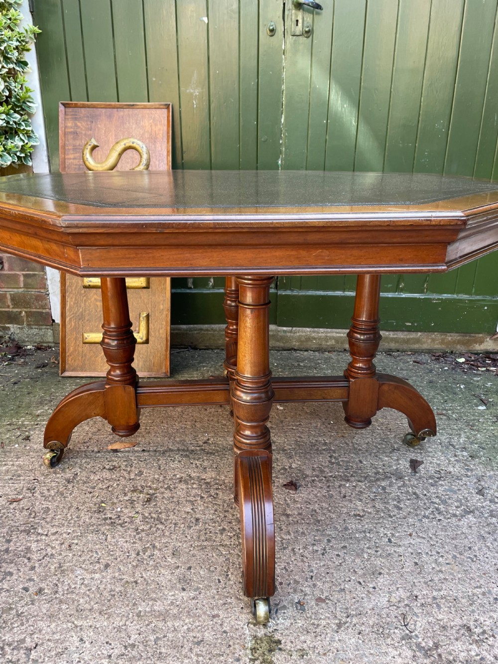 A late nineteenth-century octagonal walnut library table featuring a tooled dark leather inset top, turned legs, a cross stretcher, and brass castors. View XV