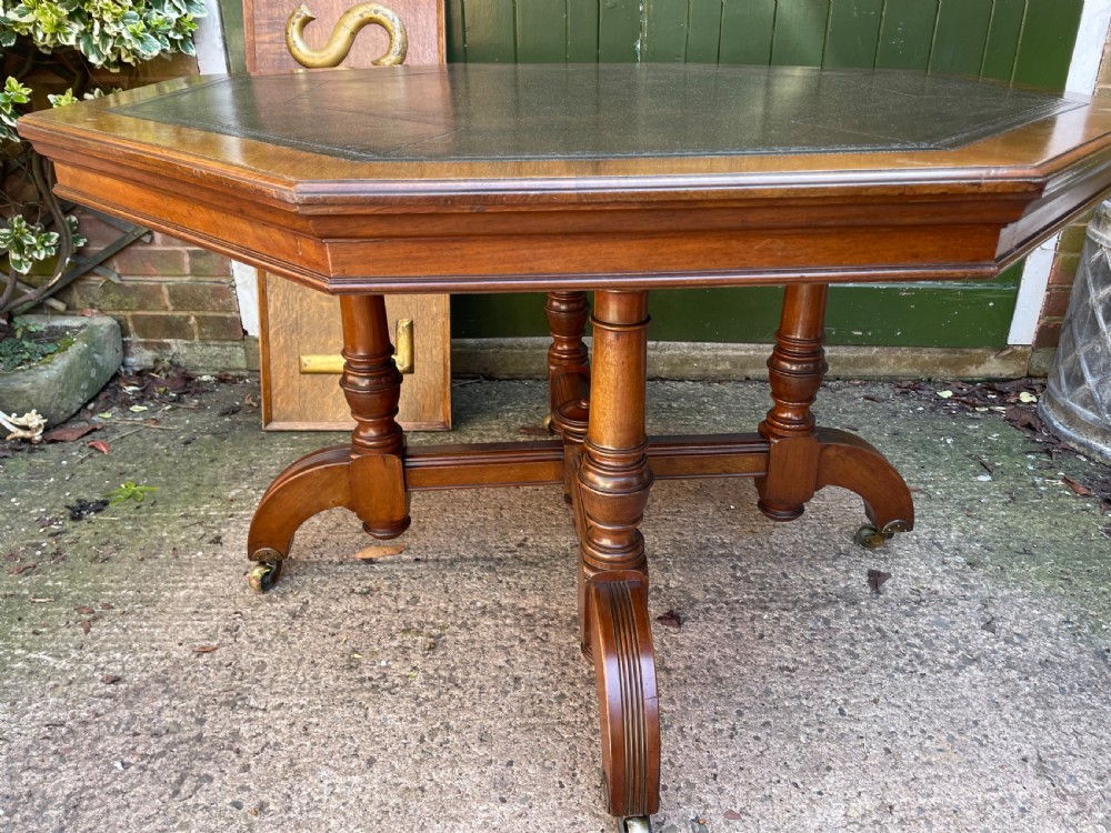A late nineteenth-century octagonal walnut library table featuring a tooled dark leather inset top, turned legs, a cross stretcher, and brass castors. View XVI