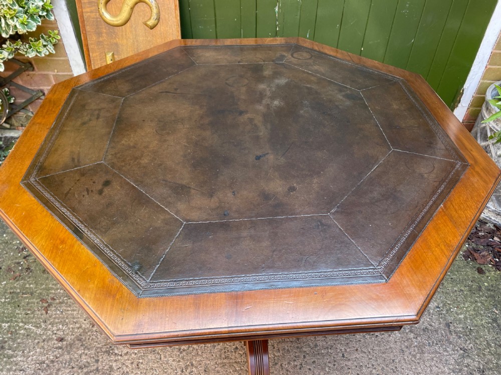 A late nineteenth-century octagonal walnut library table featuring a tooled dark leather inset top, turned legs, a cross stretcher, and brass castors. View XVII