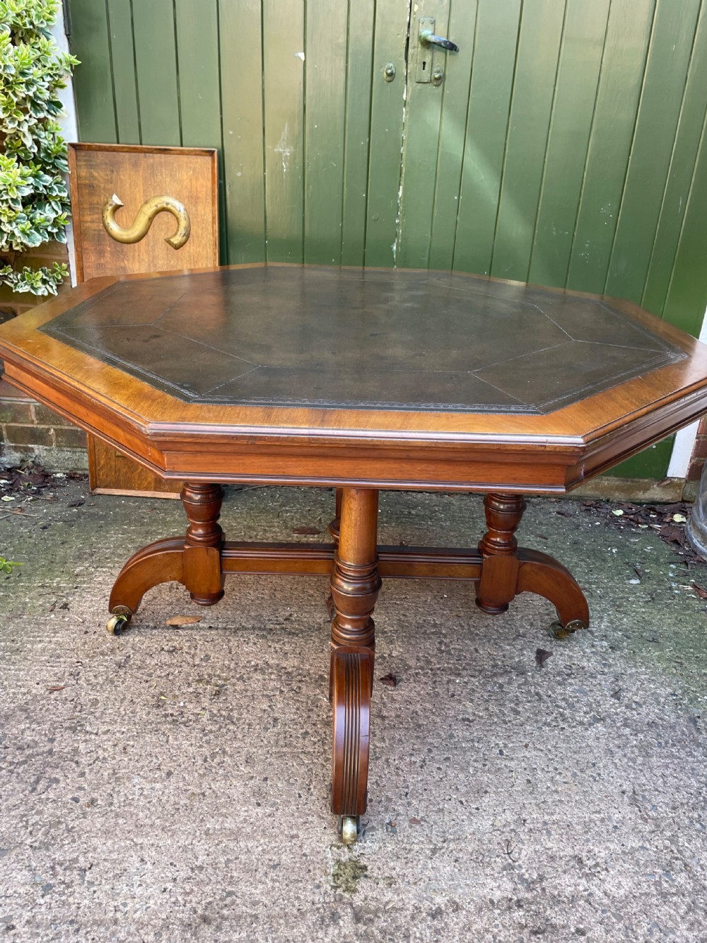 A late nineteenth-century octagonal walnut library table featuring a tooled dark leather inset top, turned legs, a cross stretcher, and brass castors. View XVIII