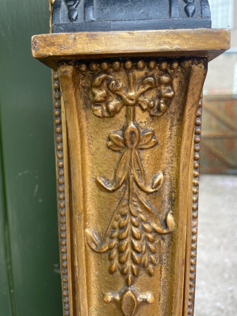 An early nineteenth-century Regency giltwood overmantel mirror featuring ball moulding along the cornice and ebonised Egyptian sphinx heads atop decorative pilasters. View VI