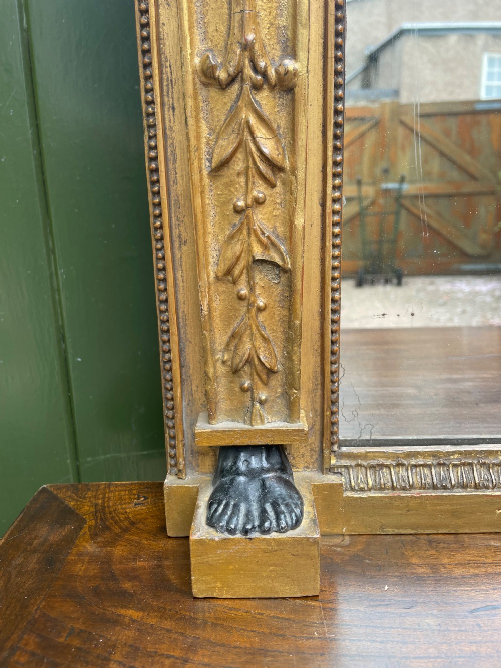 An early nineteenth-century Regency giltwood overmantel mirror featuring ball moulding along the cornice and ebonised Egyptian sphinx heads atop decorative pilasters. View IX