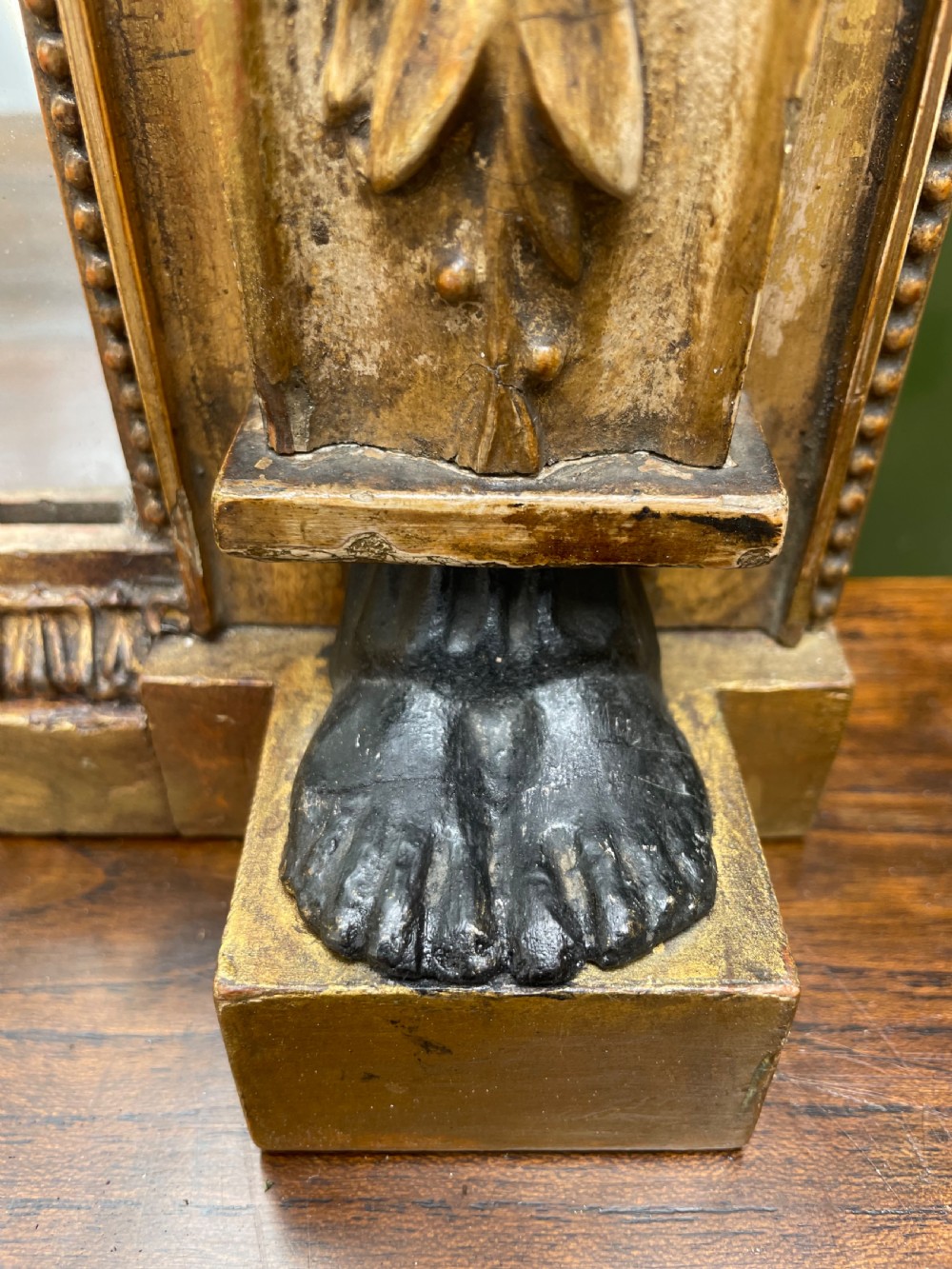 An early nineteenth-century Regency giltwood overmantel mirror featuring ball moulding along the cornice and ebonised Egyptian sphinx heads atop decorative pilasters. View XII