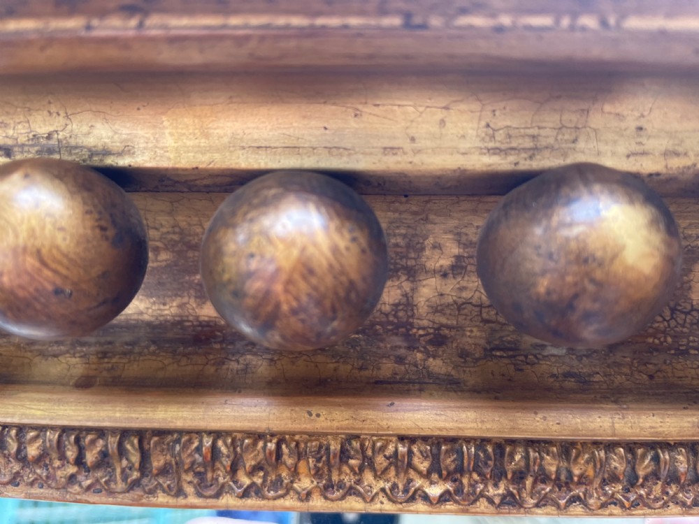 An early nineteenth-century Regency giltwood overmantel mirror featuring ball moulding along the cornice and ebonised Egyptian sphinx heads atop decorative pilasters. View XVI