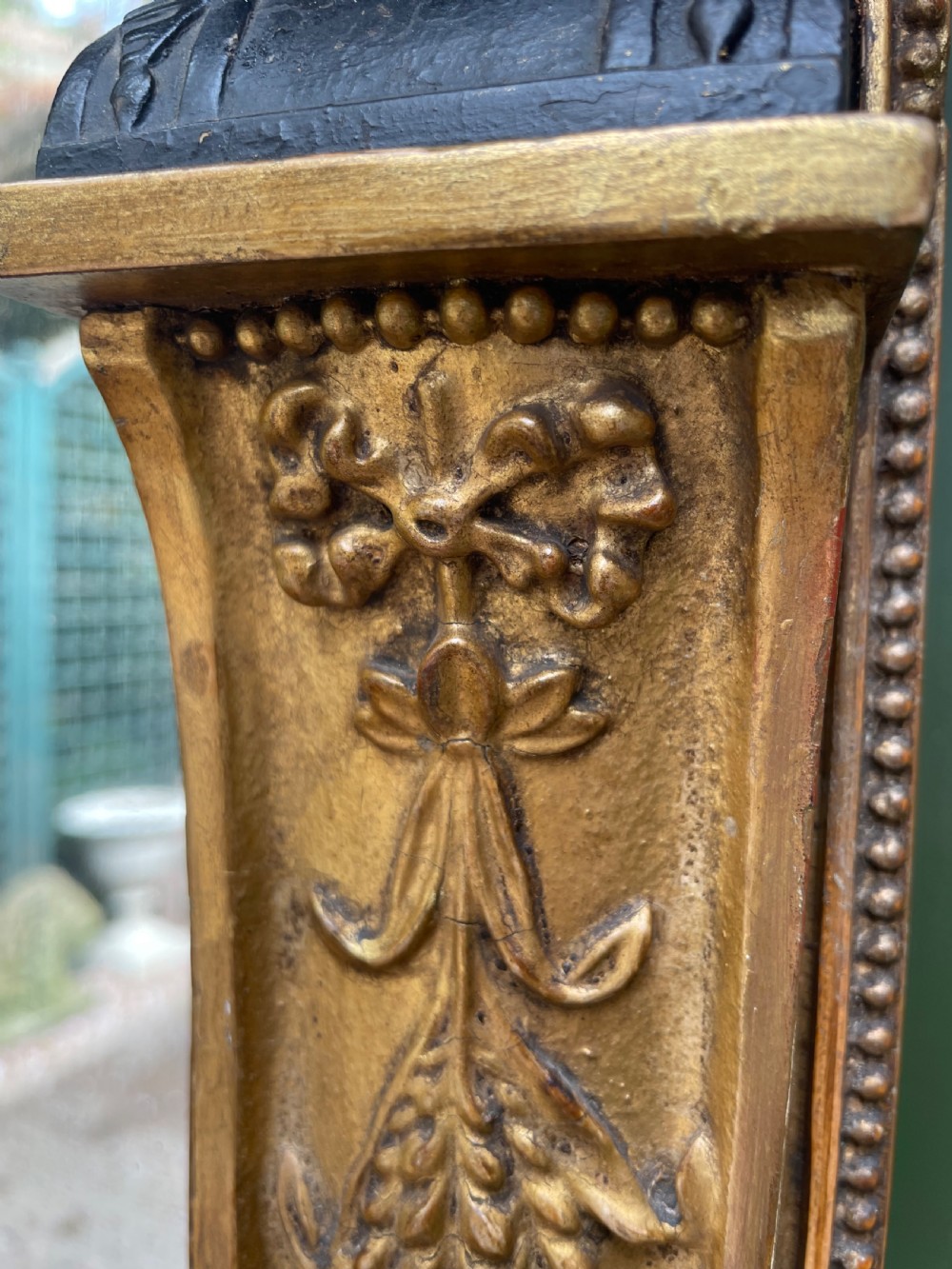 An early nineteenth-century Regency giltwood overmantel mirror featuring ball moulding along the cornice and ebonised Egyptian sphinx heads atop decorative pilasters. View XVII