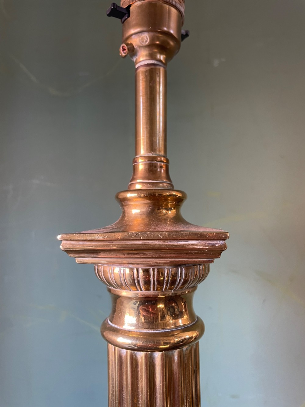 A late 19th-century brass table lamp styled as a classical fluted column with a stepped base and laurel wreath detail. View V
