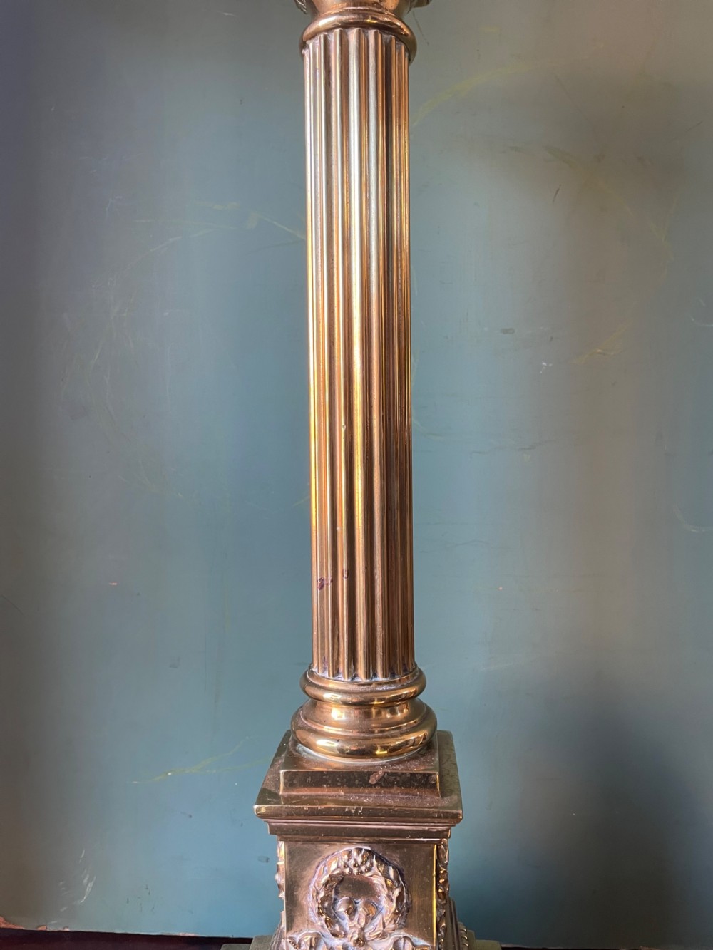A late 19th-century brass table lamp styled as a classical fluted column with a stepped base and laurel wreath detail. View X