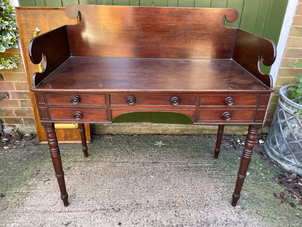 An early 19th-century George III mahogany kneehole dressing table with a scroll-ended three-quarter gallery back, multiple drawers, and ring-turned legs. View II